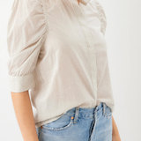 Person wearing a beige striped shirt and blue jeans on a white background