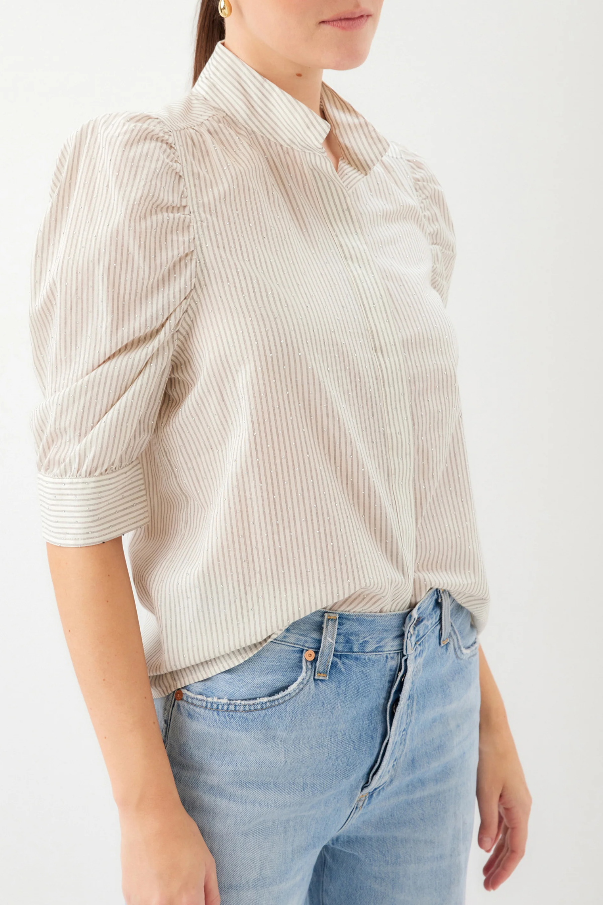 Person wearing a beige striped shirt and blue jeans on a white background