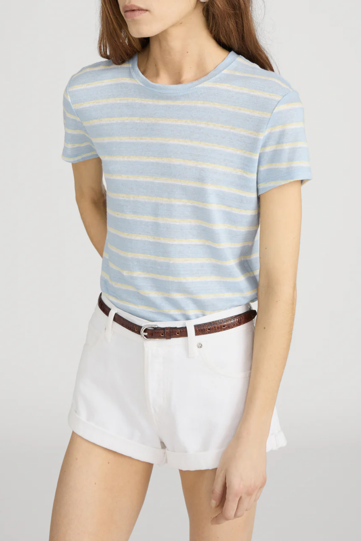 Person wearing a blue and yellow striped t-shirt and white shorts on a plain background