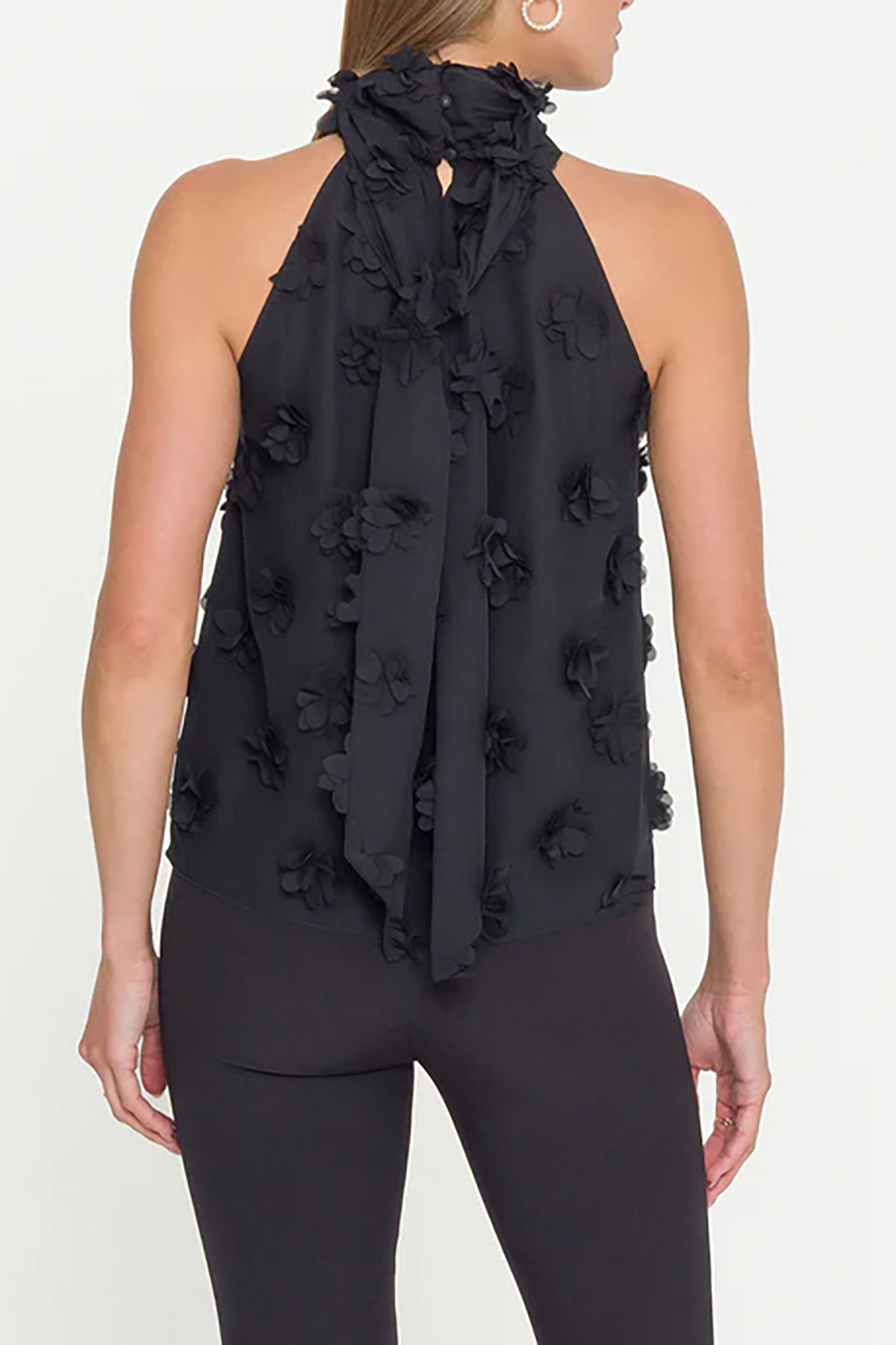 Black halter top with floral details worn by a person on a white background