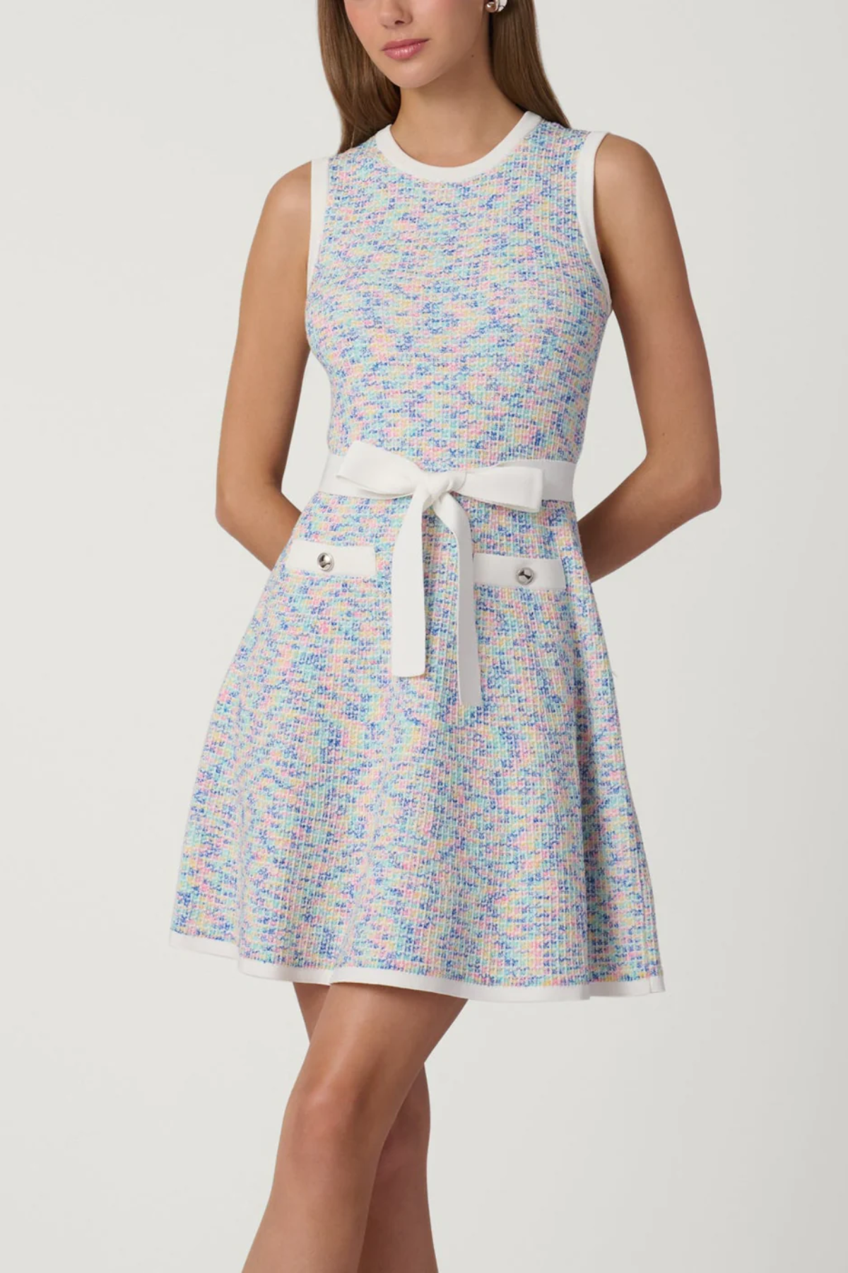 Woman wearing a patterned dress with a white belt on a plain background