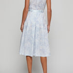 Woman wearing a light blue floral dress on a plain background