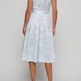 Woman wearing a light blue floral dress on a plain background