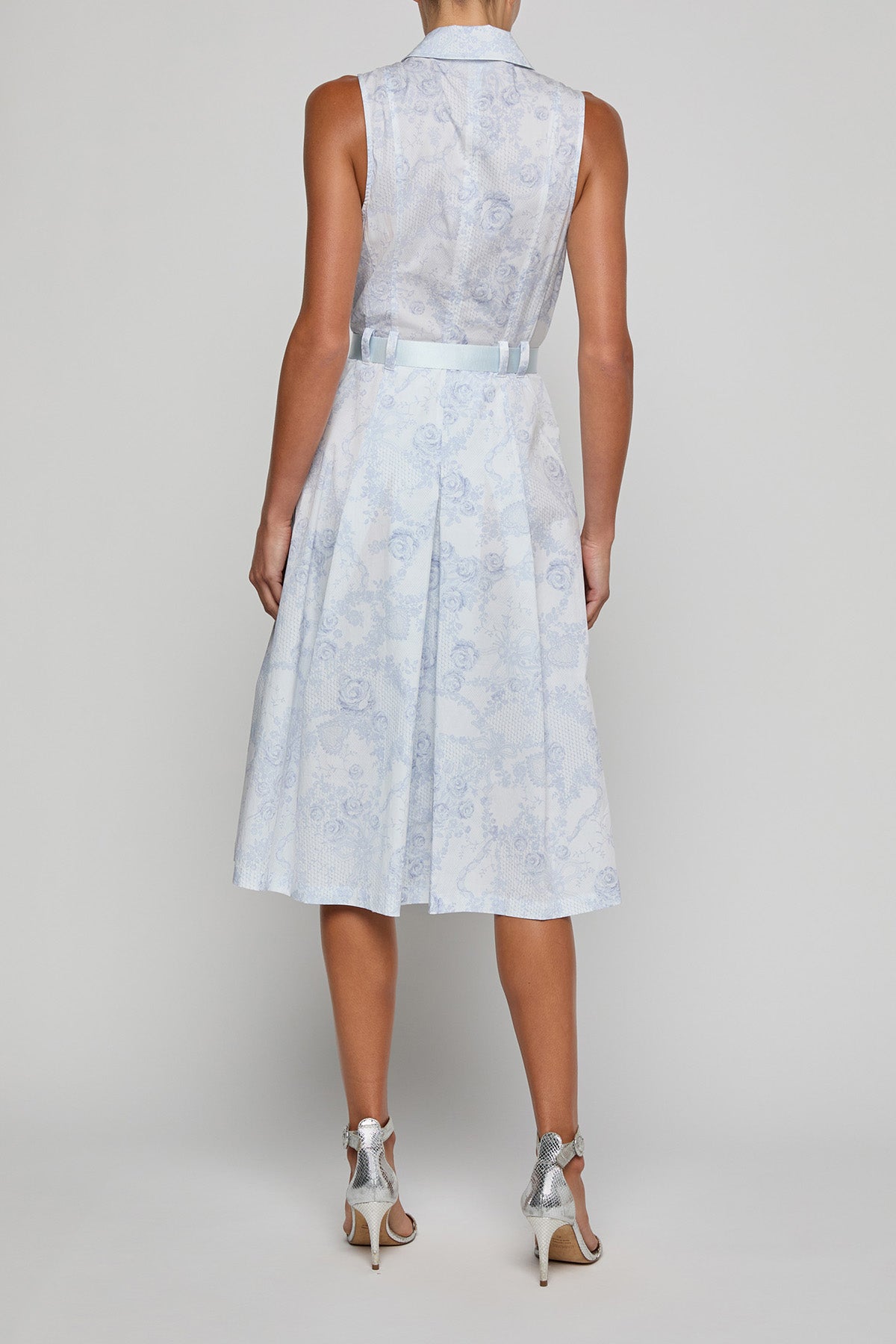 Woman wearing a light blue floral dress on a plain background