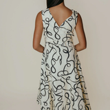 Woman wearing a white dress with black abstract pattern against a plain background