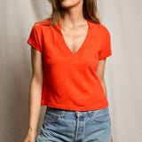 Woman wearing a red shirt and blue jeans against a neutral background