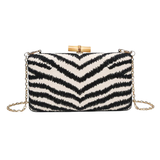 Black and white striped clutch bag with gold chain on a white background