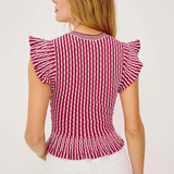 Woman wearing a red and white striped top with ruffled sleeves on a light background
