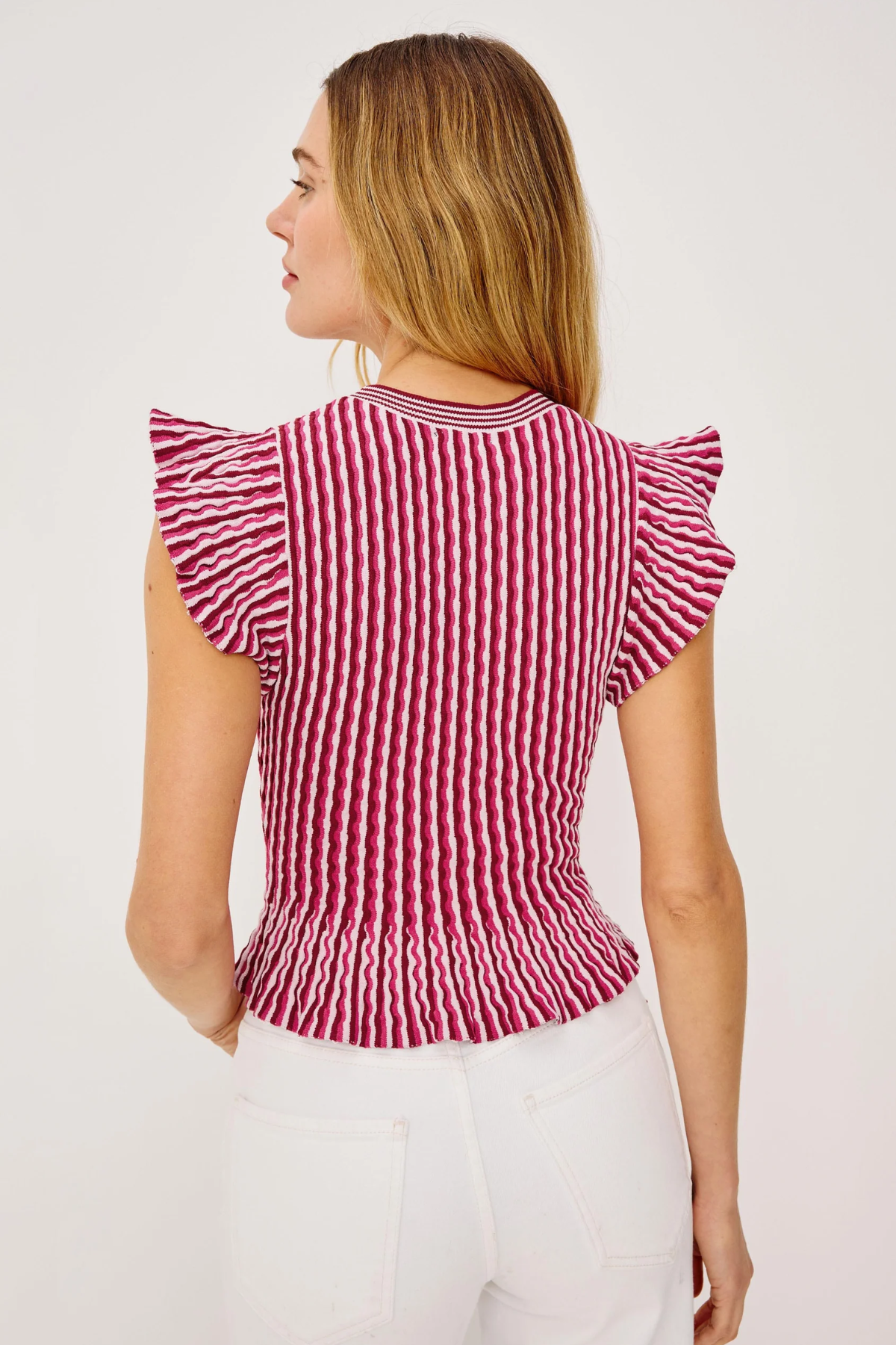 Woman wearing a red and white striped top with ruffled sleeves on a light background