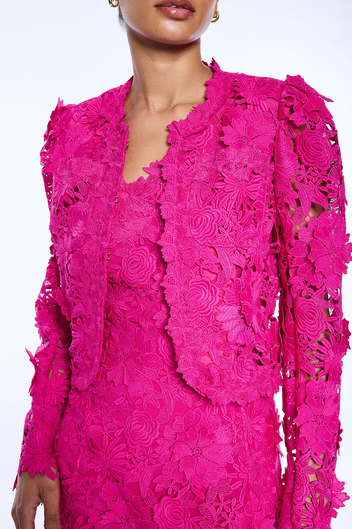 Close-up of a bright pink lace dress with long sleeves on a white background