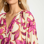 Woman wearing a floral patterned top with pink and yellow flowers on a white background