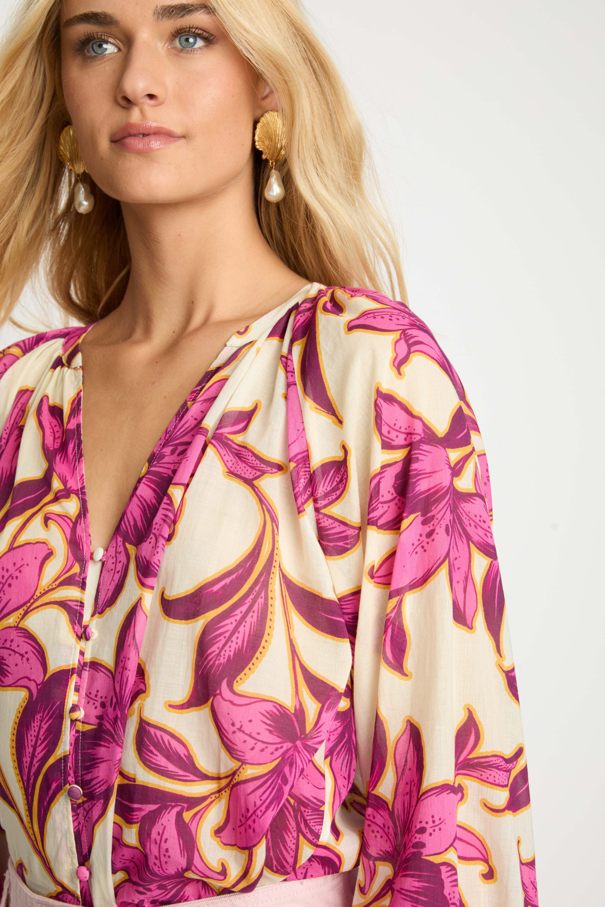 Woman wearing a floral patterned top with pink and yellow flowers on a white background