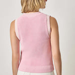 Woman wearing a pink sleeveless sweater against a plain background