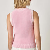 Woman wearing a pink sleeveless sweater against a plain background