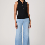 Woman wearing a black sleeveless top and light blue jeans on a white background