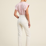 Woman wearing a pink blouse and white pants on a beige background