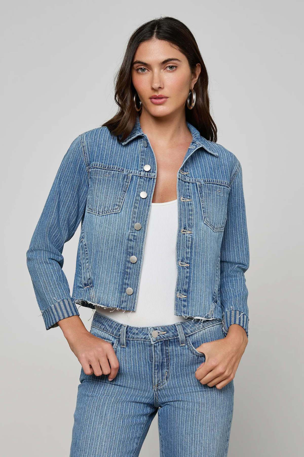 Woman wearing a blue denim jacket and jeans on a gray background