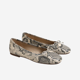 A pair of women's ballet flats featuring a black and beige snakeskin pattern, with small bow details on the toes, shown against a plain light gray background.