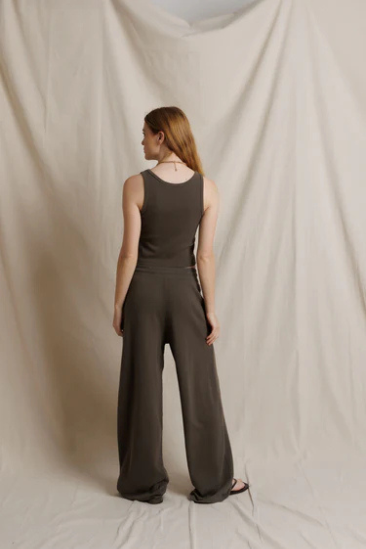 Woman wearing a brown jumpsuit against a plain background