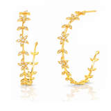 A pair of gold hoop earrings decorated with delicate leaf and flower motifs, embellished with small clear crystals, shown on a clean white background with a soft reflection.