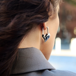 Close-up of a person wearing a heart-shaped earring with a blurred background