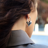 Close-up of a person wearing a heart-shaped earring with a blurred background