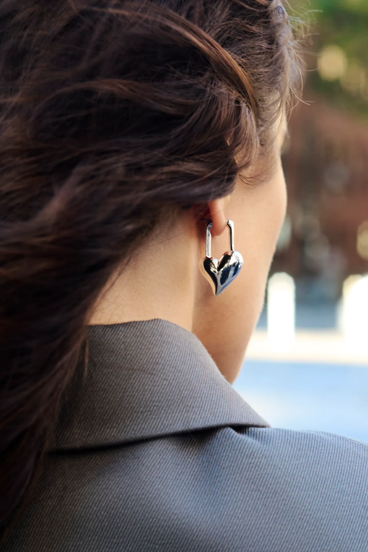 Close-up of a person wearing a heart-shaped earring with a blurred background