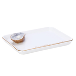 A white rectangular ceramic dish with rounded corners, a thin gold rim, and delicate gold script text along one edge, shown on a plain white background with a small oyster shell on top.