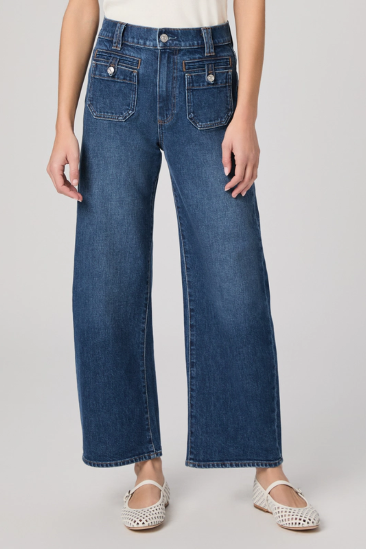 Person wearing blue jeans on a plain background