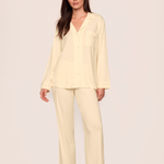 Woman wearing a light yellow pajama set against a plain background