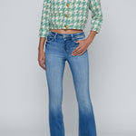 Person wearing a green patterned shirt and blue jeans on a white background