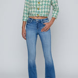 Person wearing a green patterned shirt and blue jeans on a white background