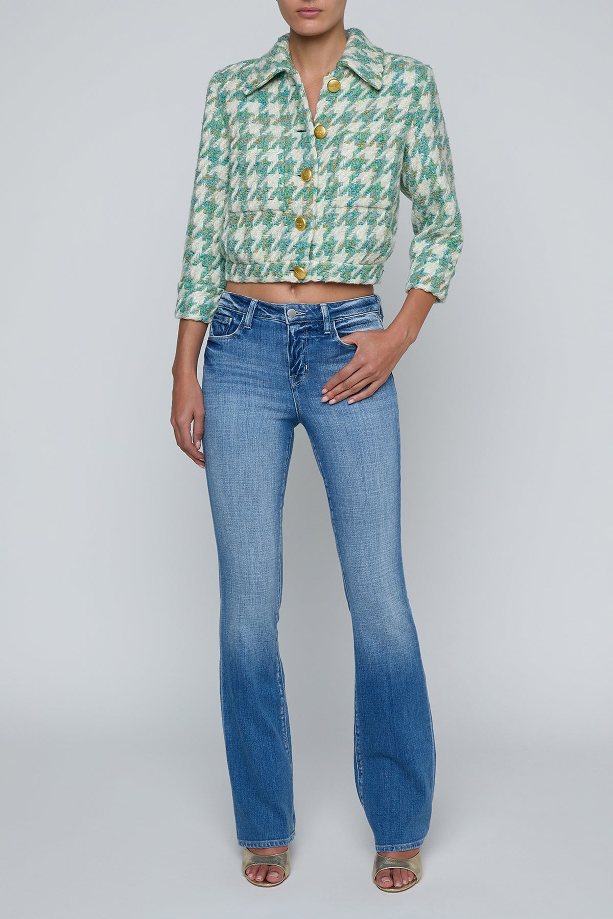 Person wearing a green patterned shirt and blue jeans on a white background