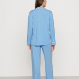Woman wearing a light blue pajama set against a white background
