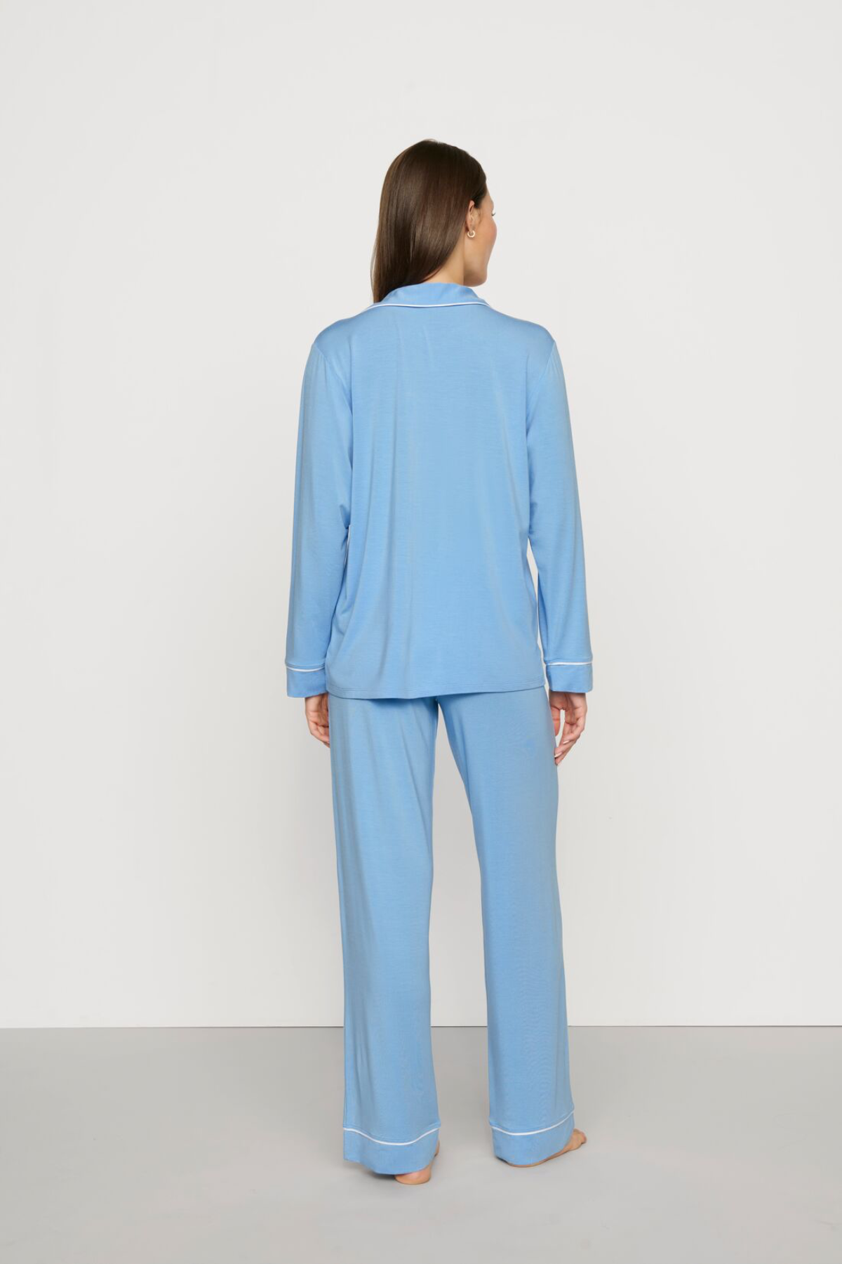Woman wearing a light blue pajama set against a white background