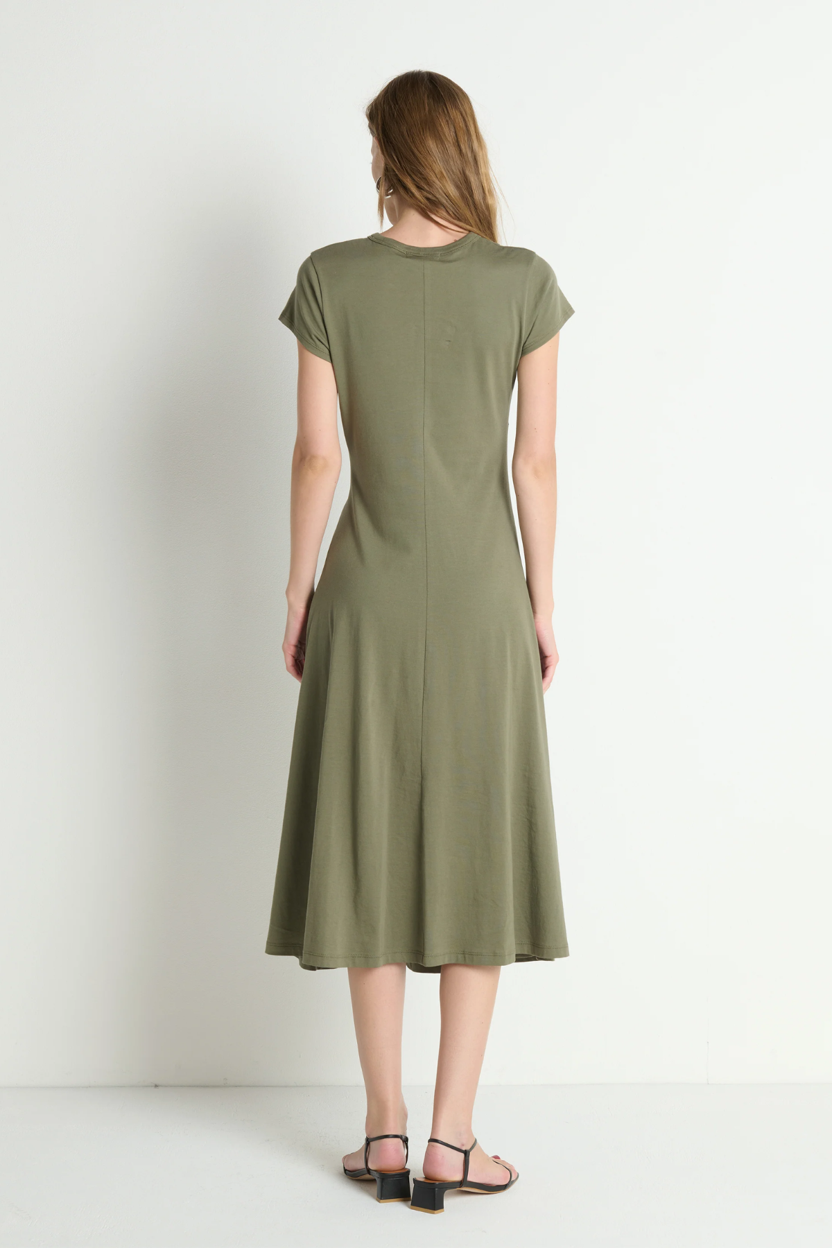 Woman wearing a green dress standing against a white background