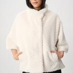 Woman wearing a white fur coat against a plain background
