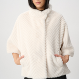 Woman wearing a white fur coat against a plain background