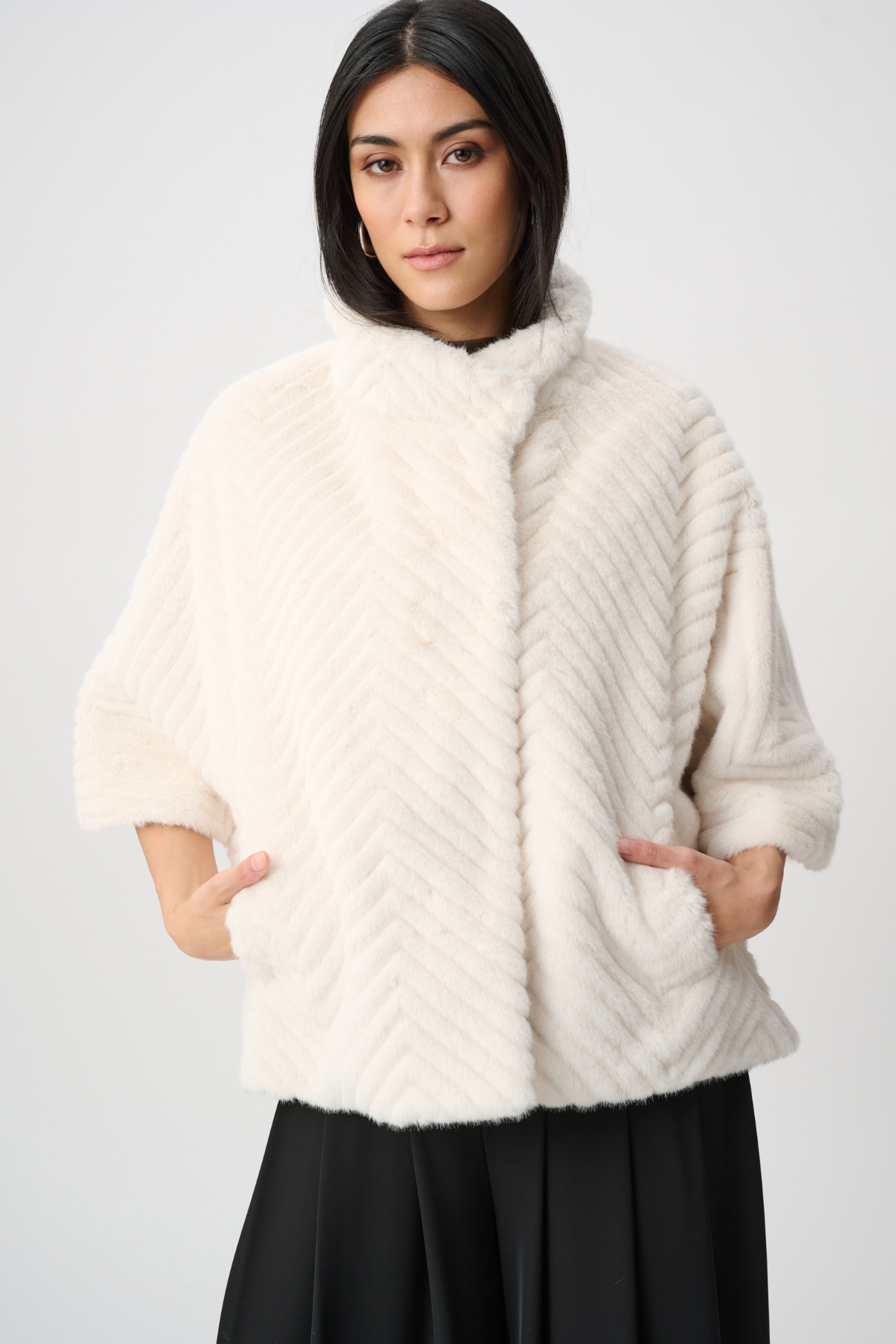 Woman wearing a white fur coat against a plain background