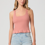 Woman wearing a pink ribbed tank top and light blue jeans on a plain background