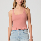Woman wearing a pink ribbed tank top and light blue jeans on a plain background