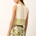 Woman wearing a white sleeveless top with green stripes and a floral skirt on a white background
