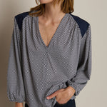 Woman wearing a patterned blouse with navy accents on a neutral background