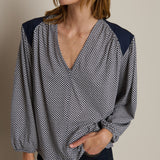 Woman wearing a patterned blouse with navy accents on a neutral background