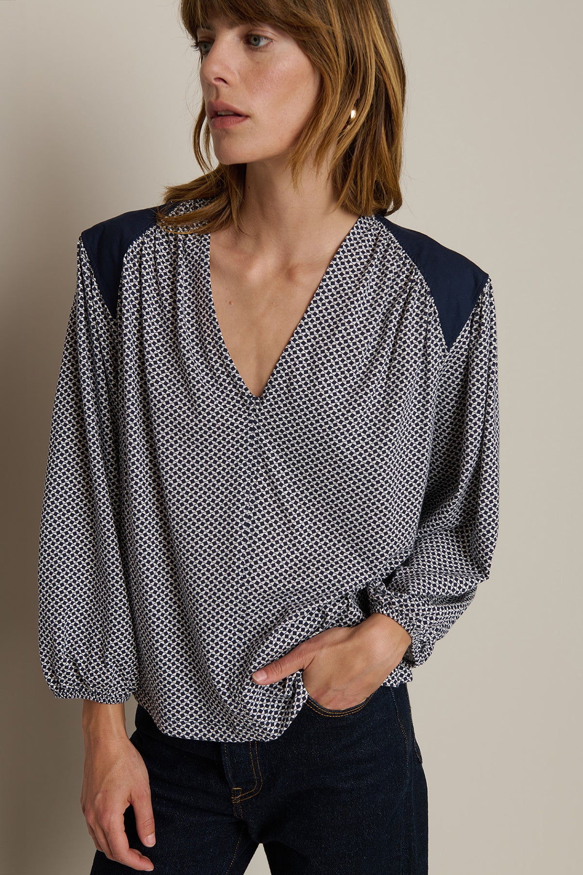 Woman wearing a patterned blouse with navy accents on a neutral background