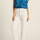 woman in blue floral blouse and white pants on tan background 