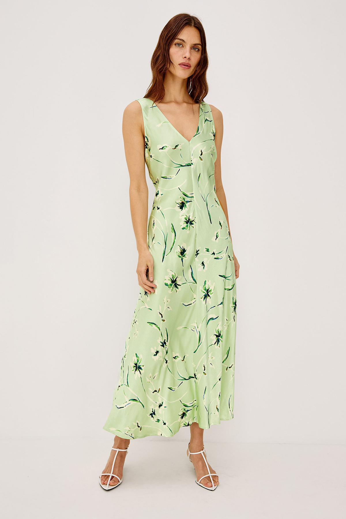 Woman wearing a light green dress with floral pattern on a white background