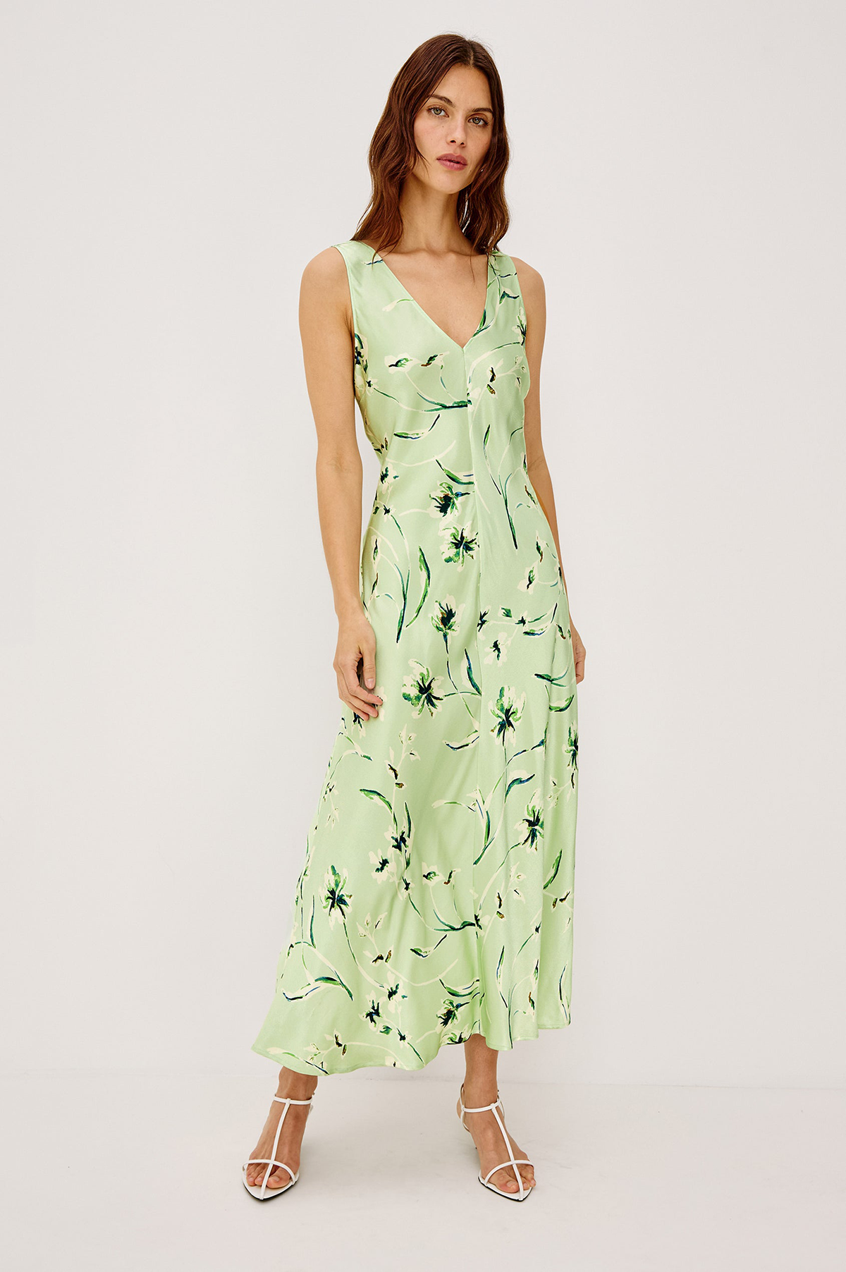 Woman wearing a light green dress with floral pattern on a white background