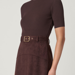 Woman wearing a brown ribbed knit top and matching skirt with a belt on a white background