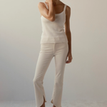woman in cream outfit and wedges on tan background 